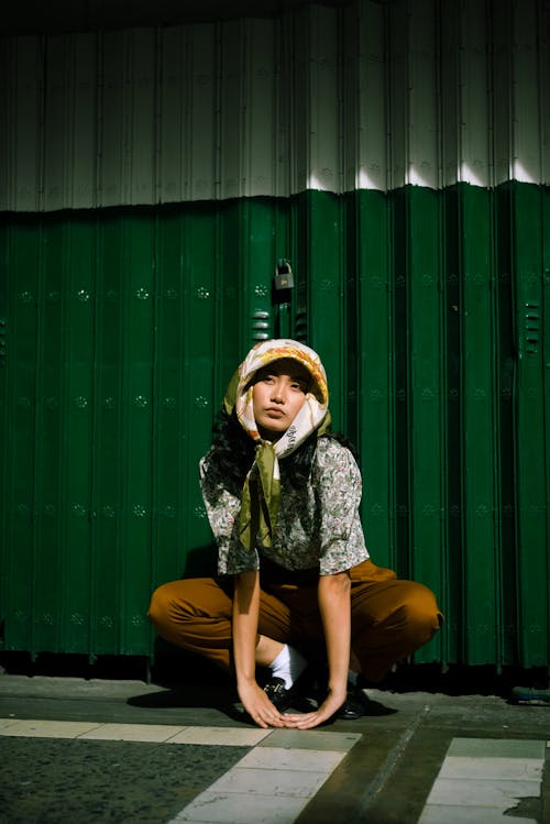 Free Photo of Woman Crouching Near Shutter Door Stock Photo