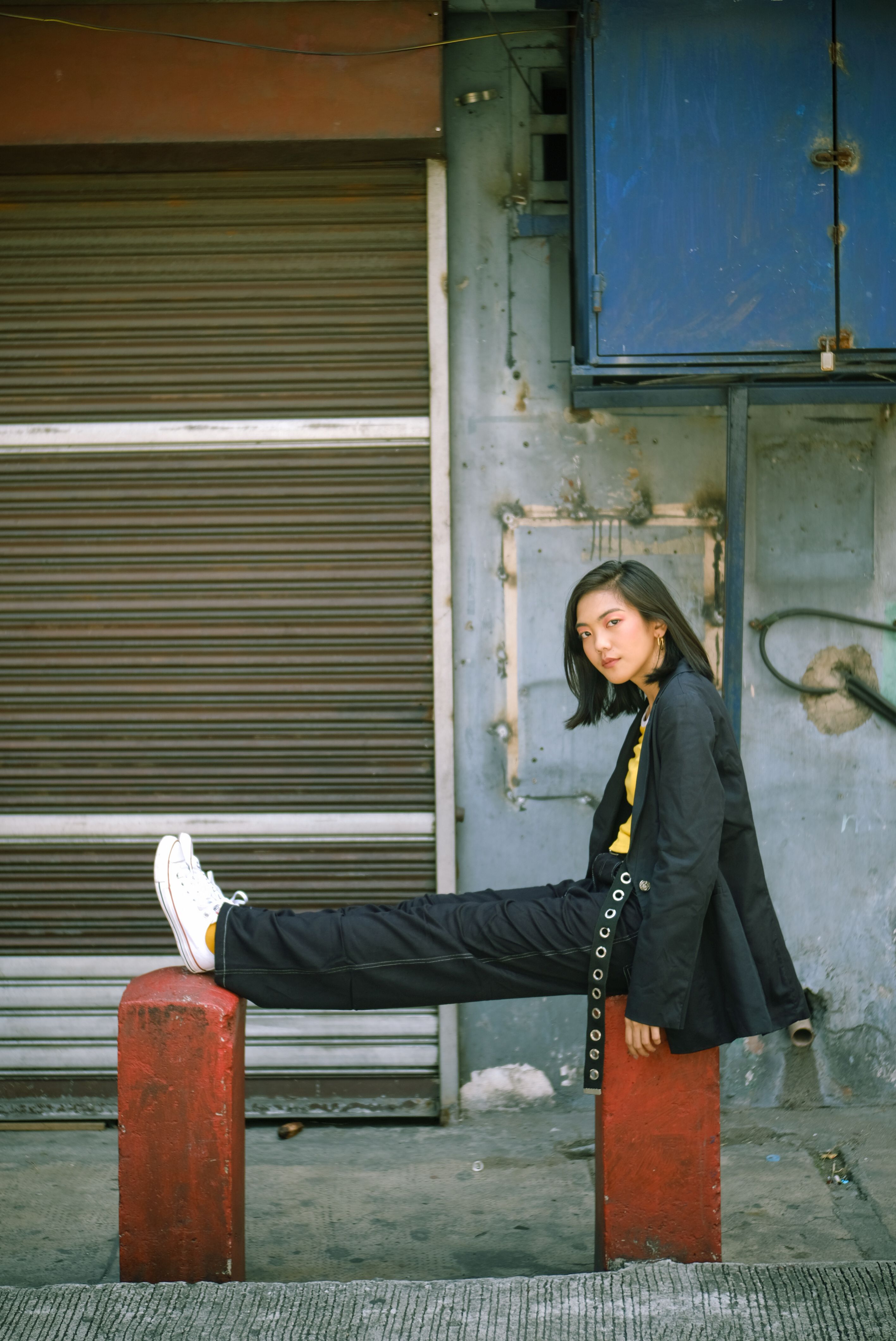 Stylish young woman posing confidently against urban backdrop in daylight.