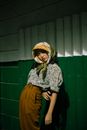 一位穿着复古服装、戴着头巾的时髦女人在户外绿墙前摆姿势