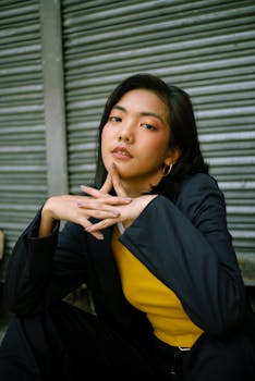 一位时尚的亚洲年轻女性在城市户外环境中自信地摆出姿势，背景是卷帘门