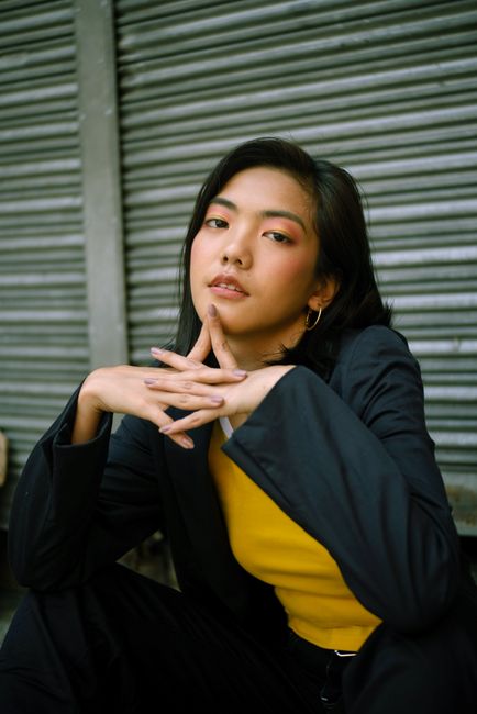 Stylish young Asian woman posing confidently in urban outdoor setting with roller shutter backdrop.