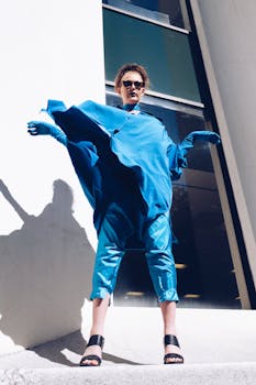 一名身穿大胆蓝色服装的女子在户外靠着城墙摆姿势