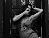 一幅引人注目的黑白肖像描绘了一位在木门前摆姿势的女人