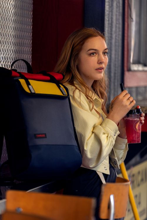 Free Young woman with long blonde hair holding a drink inside a modern space. Stock Photo