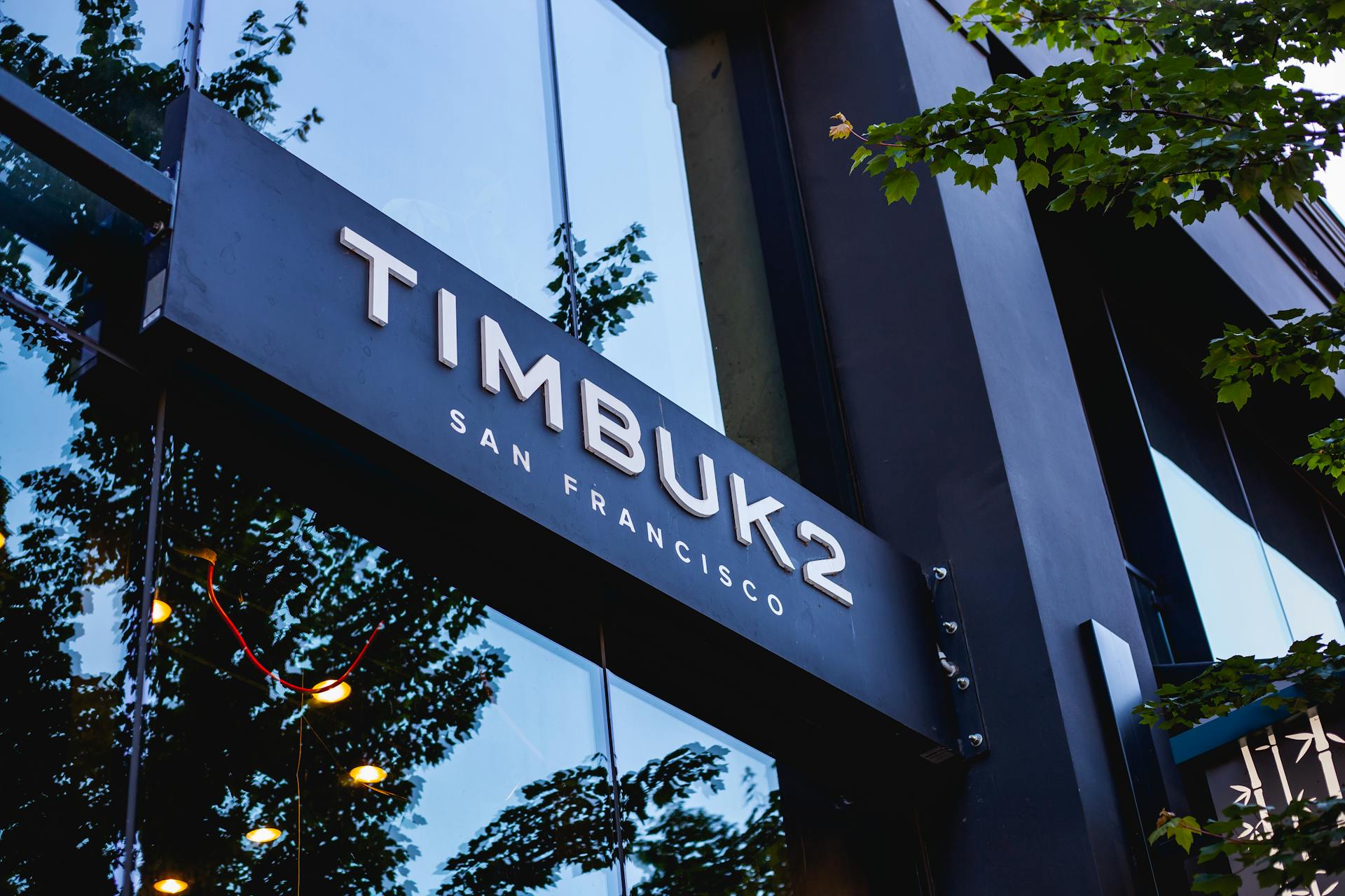 Vue en angle bas de l'extérieur du magasin Timbuk2 à San Francisco avec des reflets sur la façade en verre.