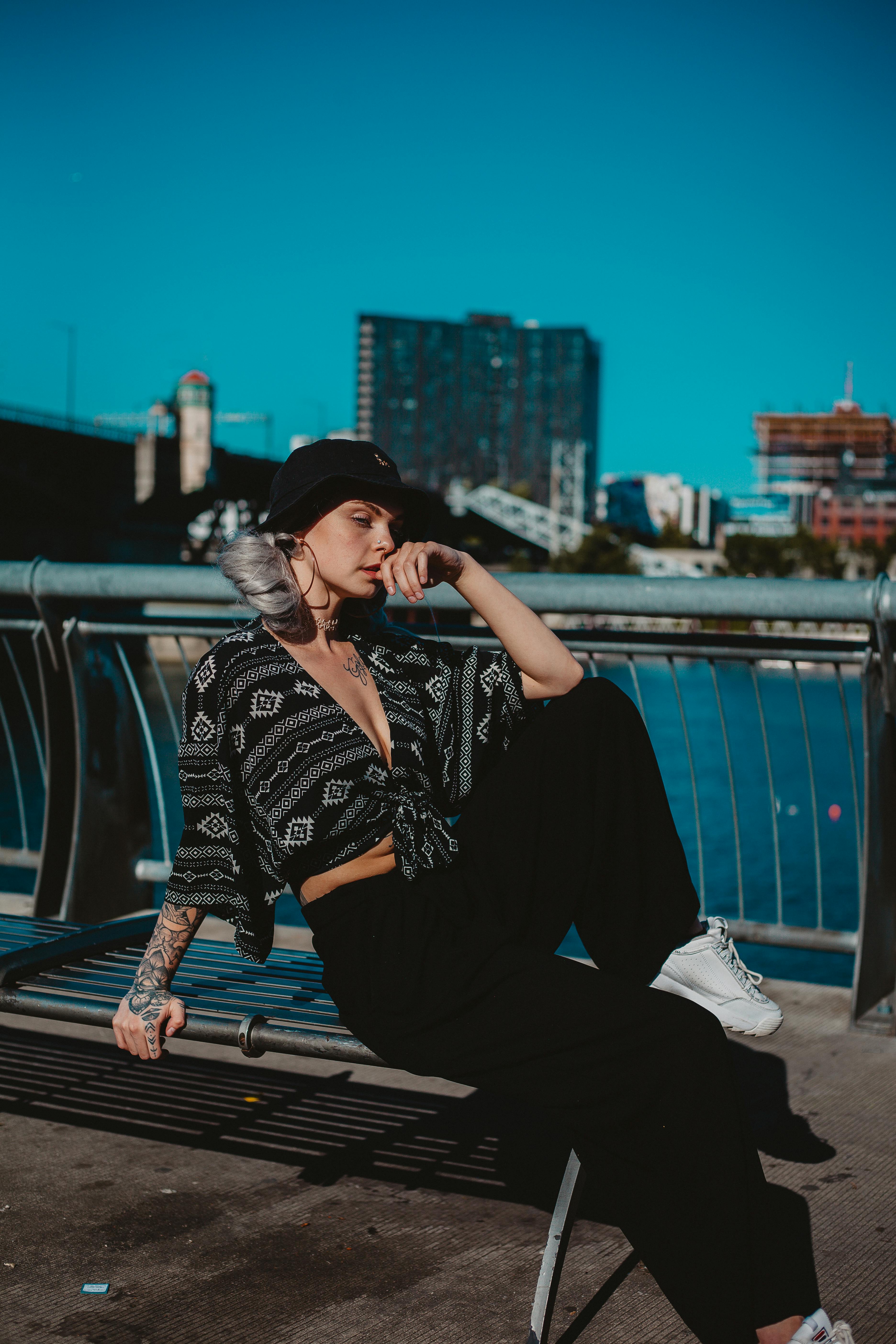 在城市的河畔，一位时尚女性沐浴着日光，摆出姿势，展现现代风尚