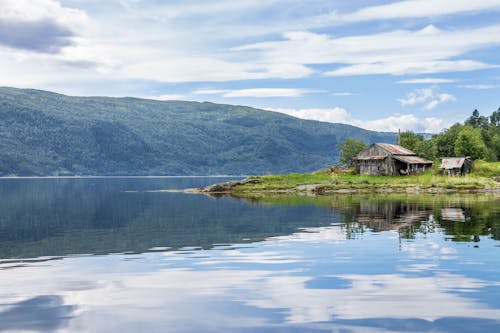 Brown House Near Body of Water Under White Sky