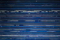 蓝色金属快门上油漆剥落和水平条纹的详细视图