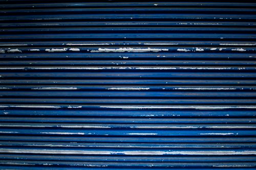 Free A detailed view of a blue metal shutter with peeling paint and horizontal stripes. Stock Photo