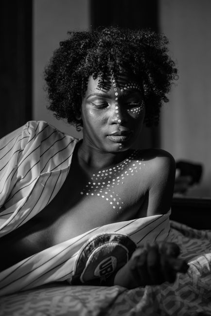 Black and white portrait of a woman with artistic body paint, expressing elegance.
