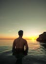 在菲律宾米沙亚斯中部，一名男子站在水中，放松地观察着宁静的海洋日落