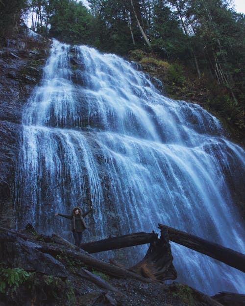 Free Woman Standing Under Waterfalls Stock Photo