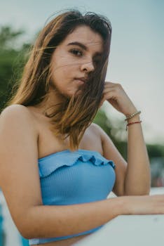 一位穿着蓝色露脐上衣的时尚年轻女子，正在户外享受阳光明媚的一天