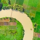 航拍图像展现了郁郁葱葱的绿色农田与蜿蜒的河流，凸显了乡村的农业风貌