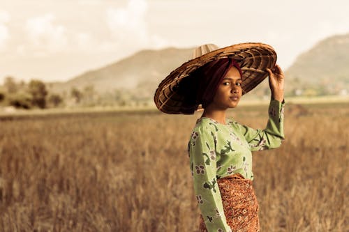 Foto Wanita Berdiri Saat Mengenakan Topi Jerami