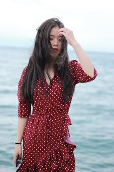 一张迷人的照片中，一位身穿红色连衣裙的女子站在吉尔吉斯斯坦的伊塞克湖畔