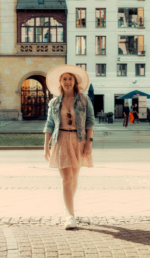 Free Confident woman in a dress and hat strolling through urban Magdeburg on a sunny day. Stock Photo