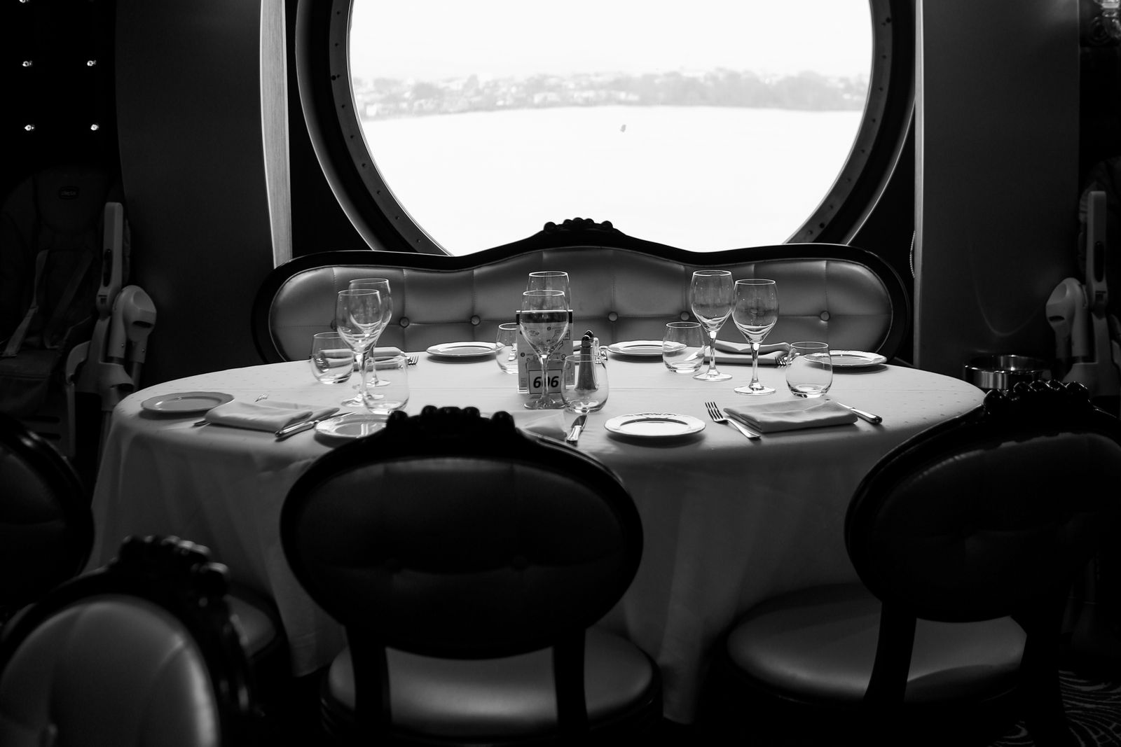 A table set for dinner beside a round window on a river cruise boat
