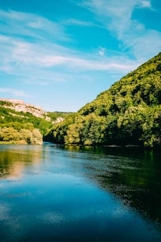 一条宁静而风景优美的河流，在充满活力的蓝天下，蜿蜒流淌于郁郁葱葱的绿色植物之中