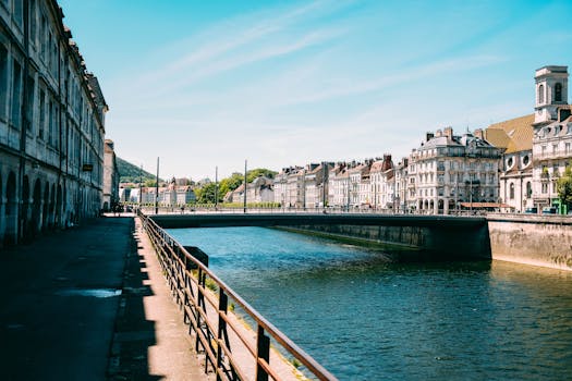 Tranquil cityscape with historic buildings lining a peaceful canal under a clear blue sky.
