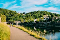 夏季，两名骑行者沿着绿树成荫、风景如画的河畔小路骑行