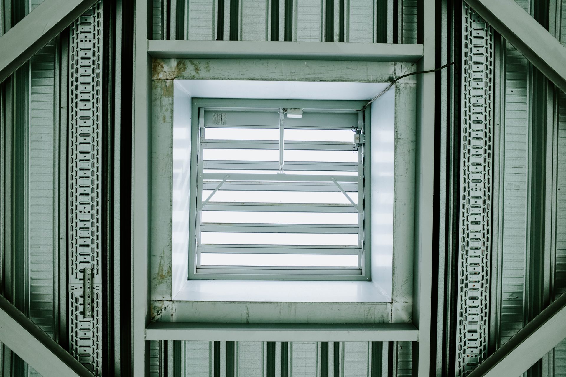 Modern architectural ceiling structure featuring a metallic ventilation grid.