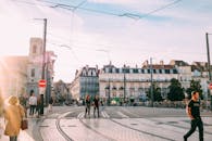 人们走过一座阳光明媚的欧洲历史名城的有轨电车十字路口