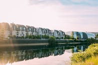 阳光明媚的城市住宅区里，现代建筑沿着宁静的河流倒映在充满活力的天空下