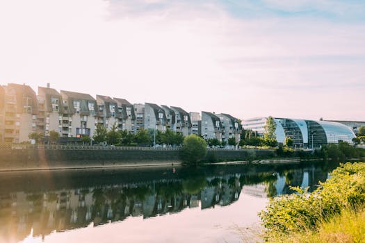 阳光明媚的城市住宅区里，现代建筑沿着宁静的河流倒映在充满活力的天空下