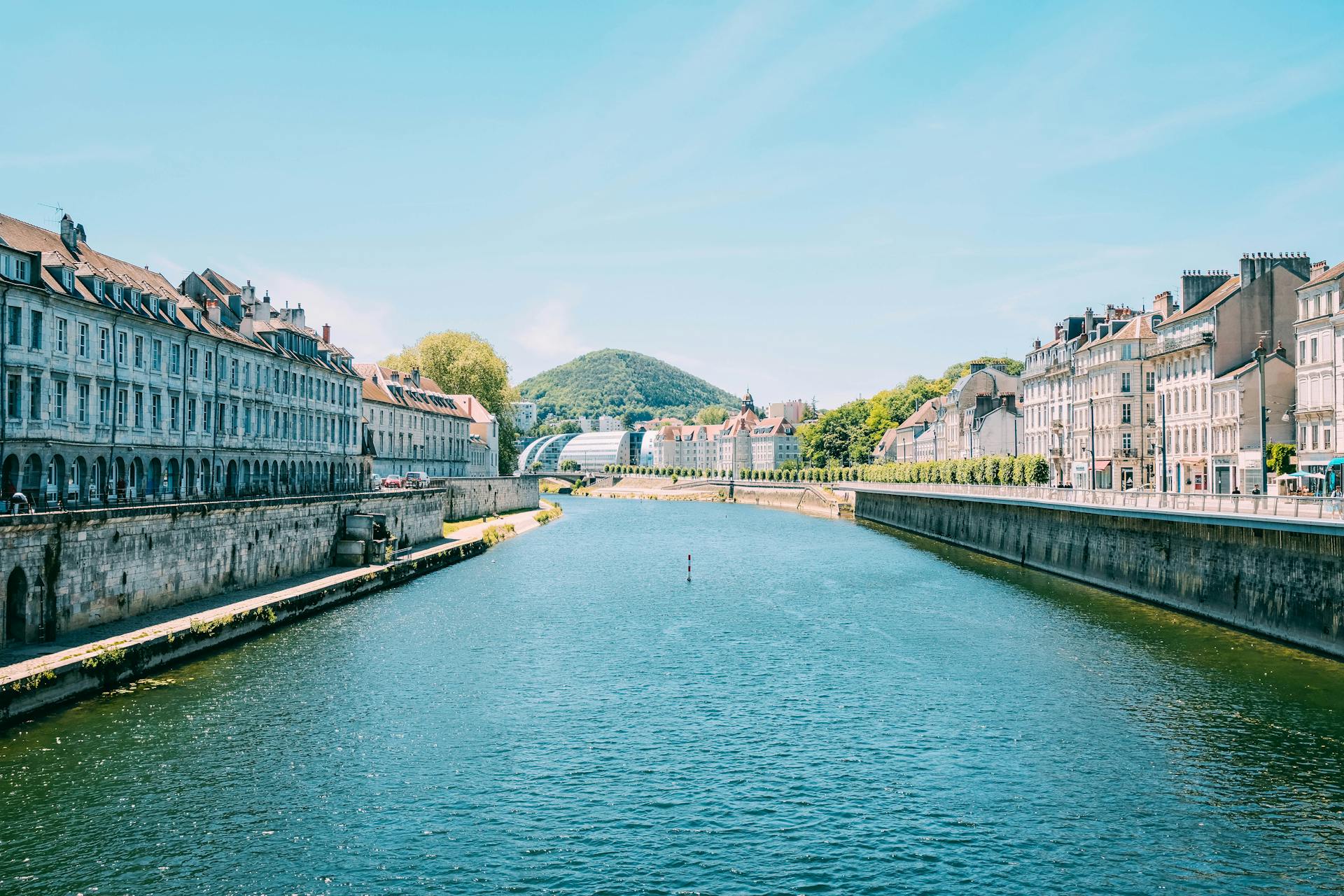 Scenic view of historic buildings lining a tranquil canal under a clear blue sky.