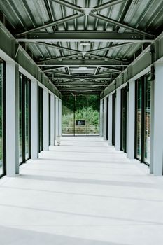这条明亮的现代走廊设有玻璃墙和金属天花板，展现了当代建筑风格