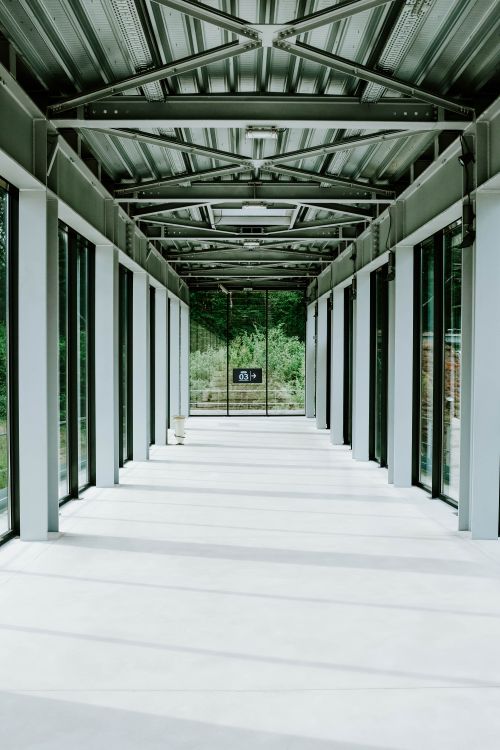 Free Bright modern corridor with glass walls and a metal ceiling, showcasing contemporary architecture. Stock Photo