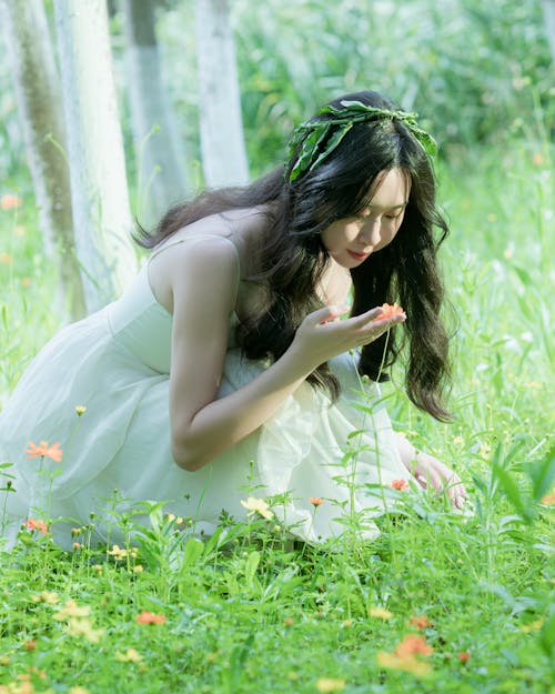 A woman in a white dress is kneeling in the grass
