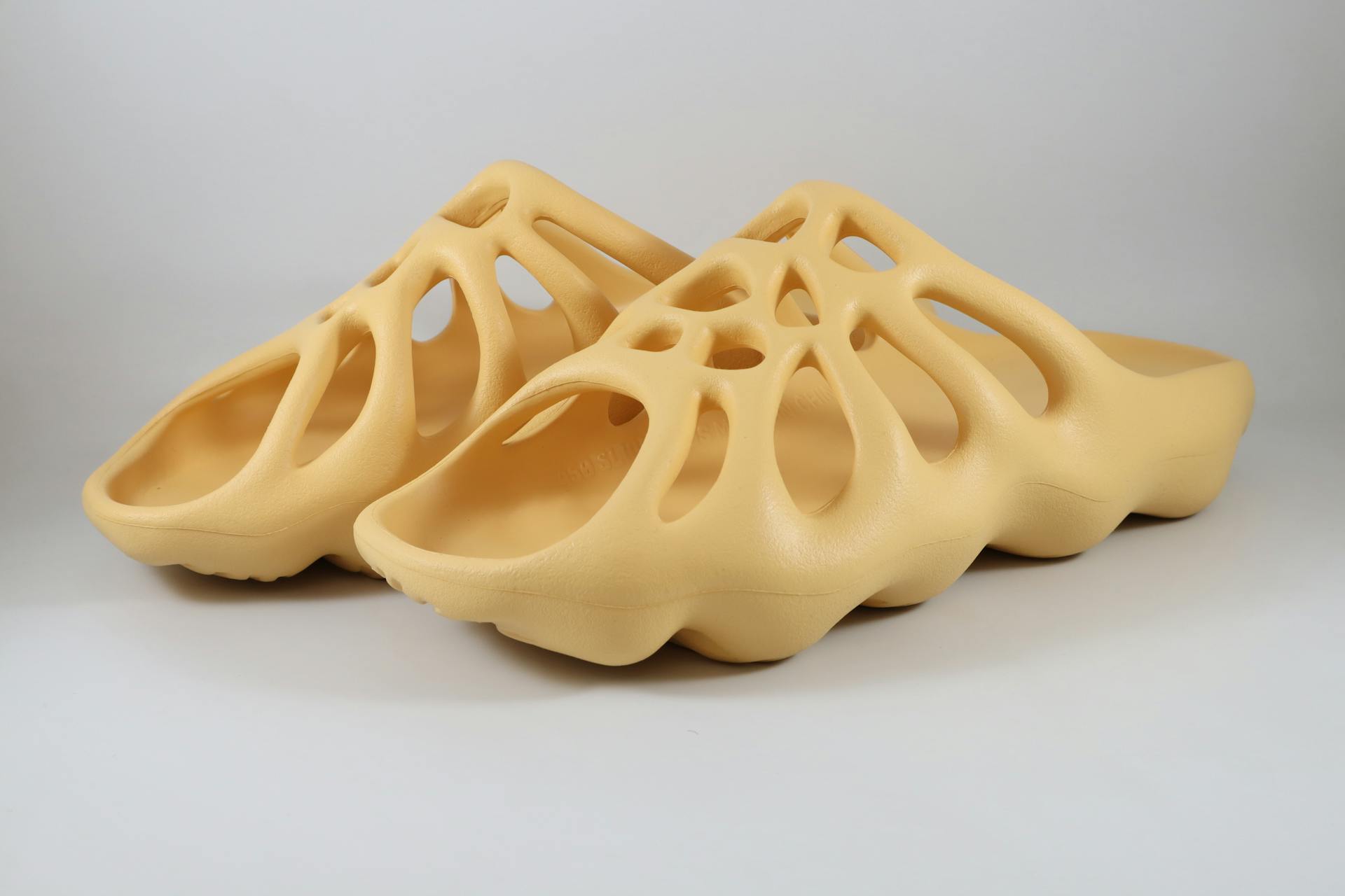 Stylish 3D-printed beige slippers with unique design on a white background.