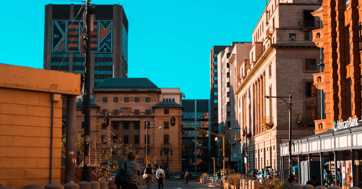 A vibrant city street scene with people walking among urban architecture and buildings.