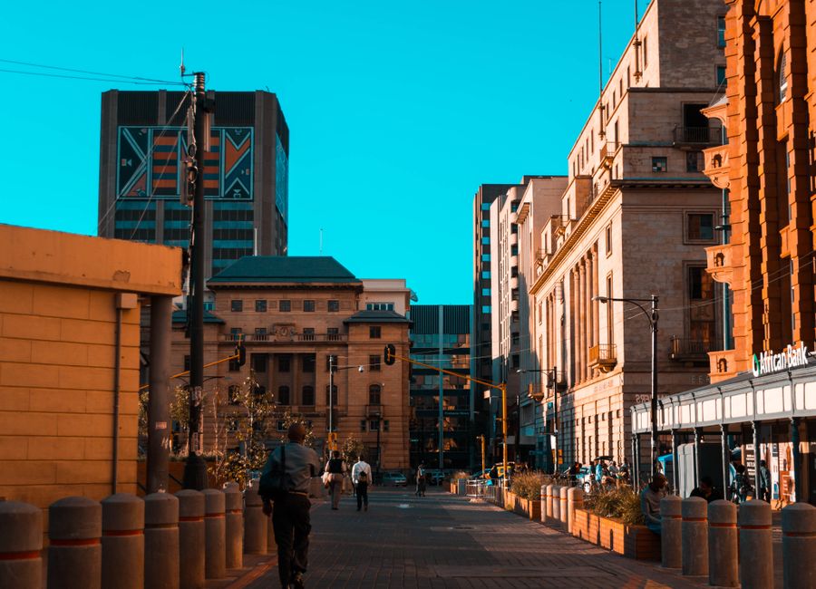 A vibrant city street scene with people walking among urban architecture and buildings.