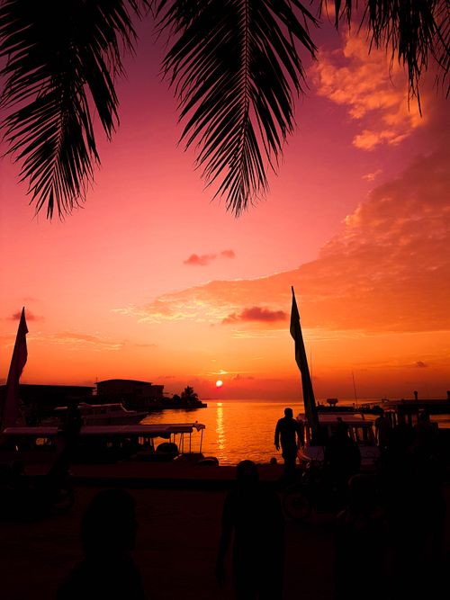 Free Experience a stunning sunset over the Maldives with silhouettes against a vibrant sky. Stock Photo