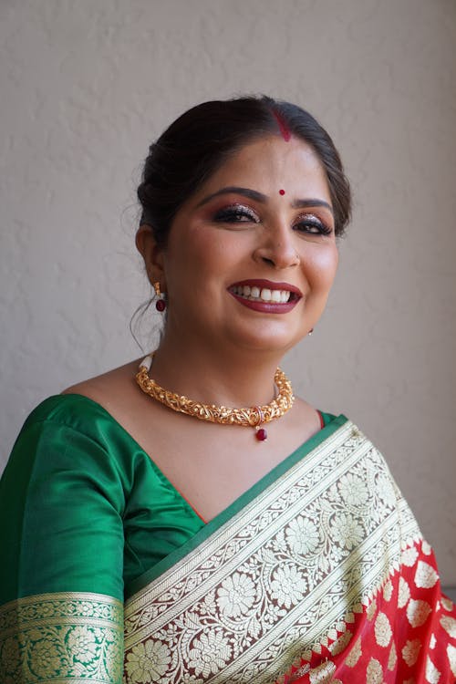A smiling woman in a red and green sari