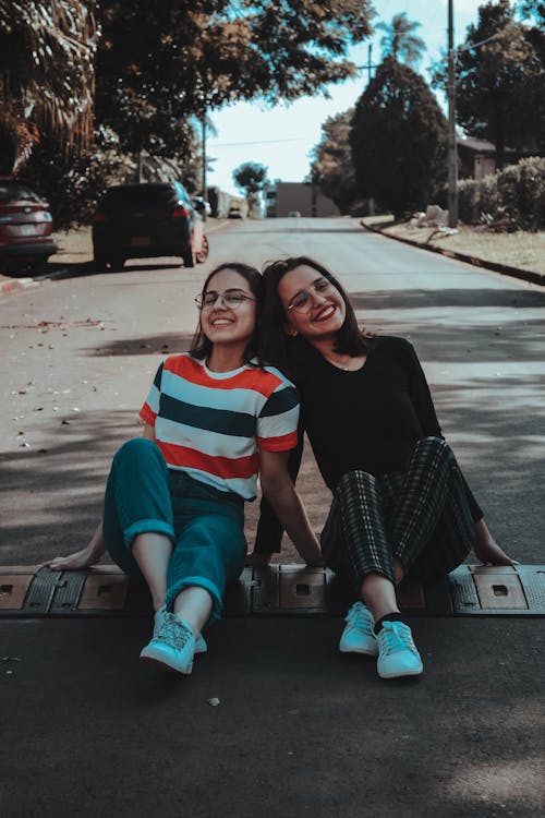 Photo of Two Women Sitting on Road