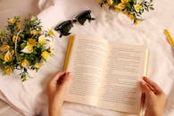 阳光明媚的日子里，我戴着太阳镜，手里拿着一本书，周围是黄色的花朵