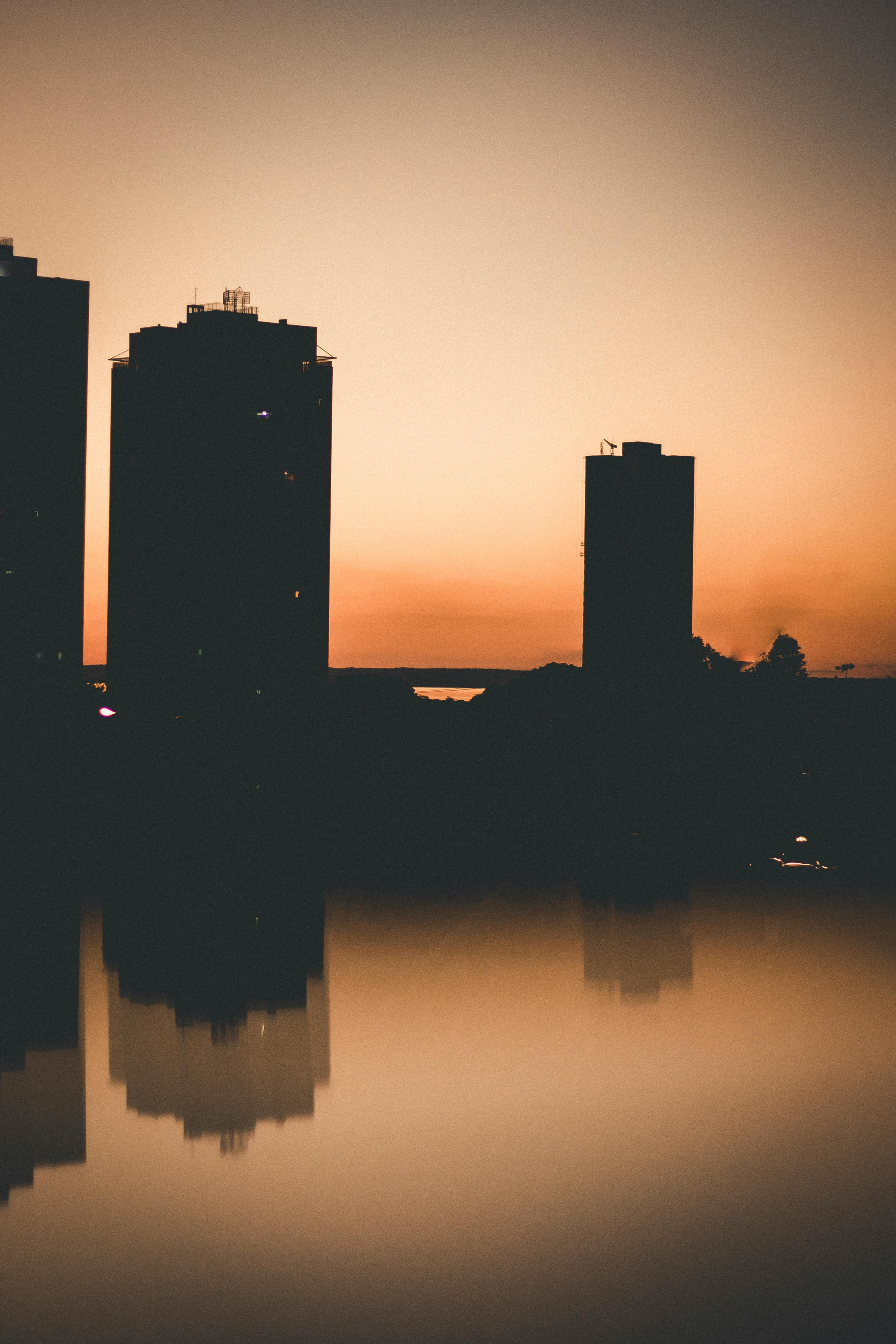 日落时分，建筑物的剪影倒映在波光粼粼的水中