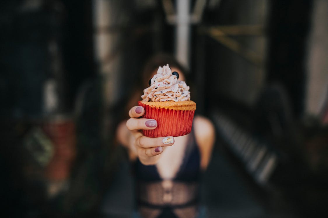 Fotografía De Enfoque Selectivo De Mujer Sosteniendo Cupcake