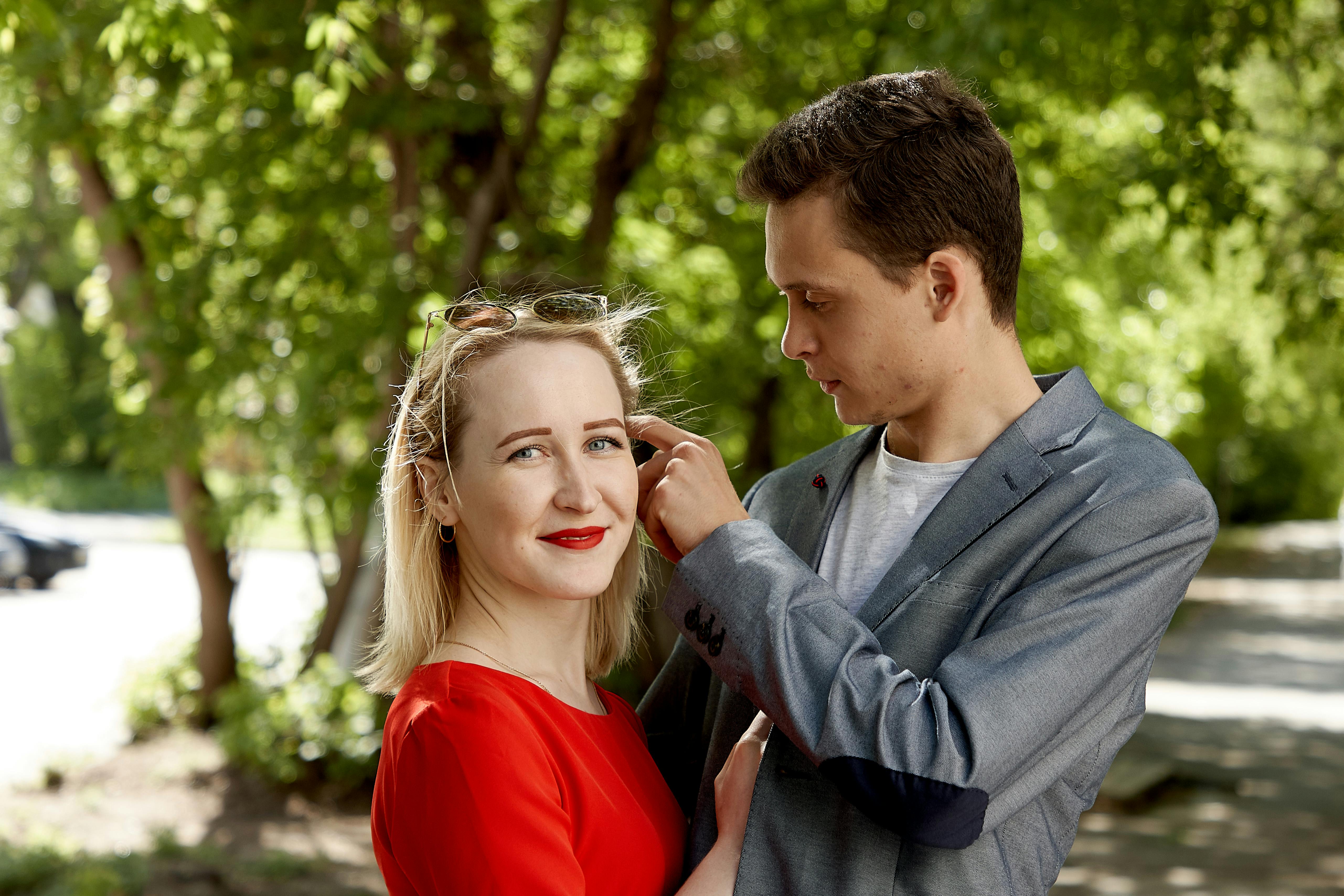 A loving couple enjoying a sunny day in a lush park setting, capturing a warm moment.
