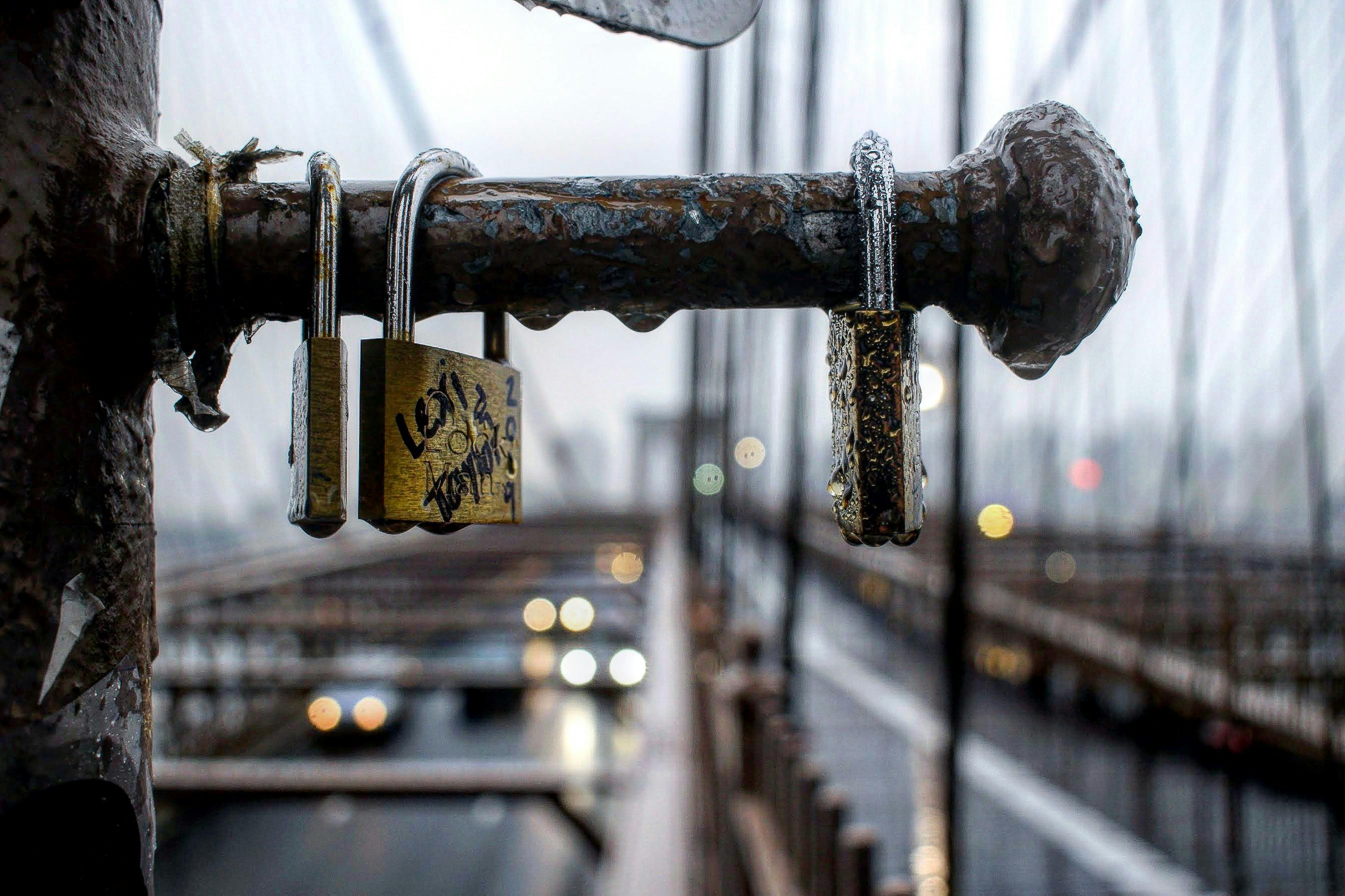 以散景城市景观为背景，拍摄潮湿城市桥梁上生锈挂锁的特写镜头