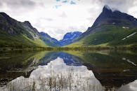 挪威山脉的壮丽景色倒映在宁静的湖泊中，展现了大自然的静谧之美