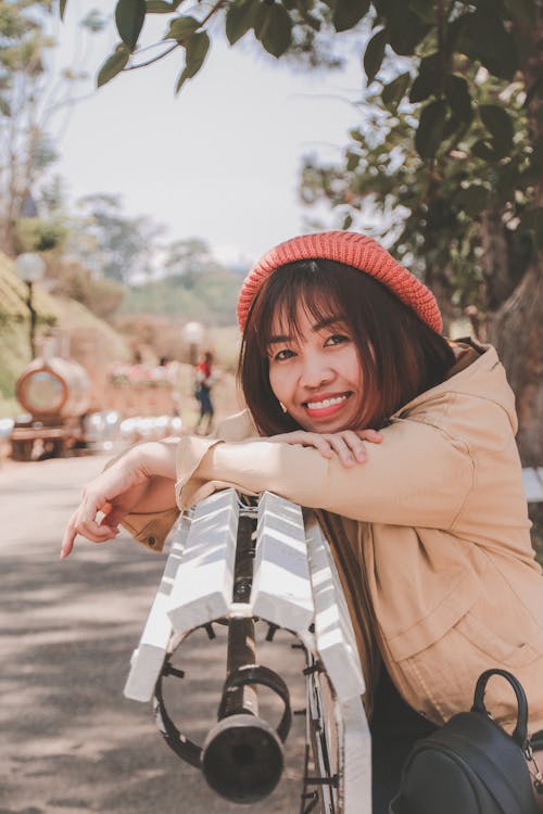 Foto De Mulher Sorridente, Apoiada Em Um Banco De Madeira Branco