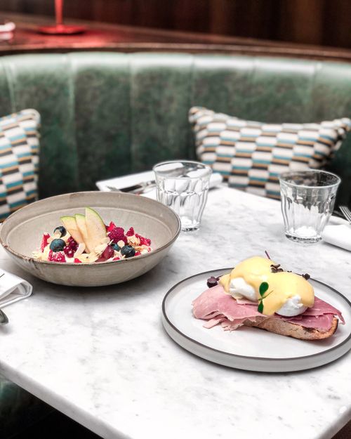Free A delicious breakfast of eggs benedict and fruit bowl in a chic Parisian cafe setting. Stock Photo