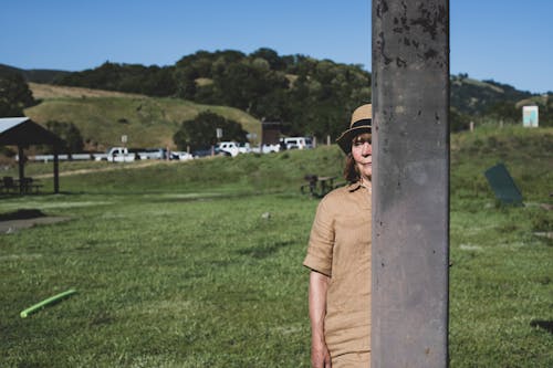 Photo of Woman Wearing Sun Hat While Hiding Behind Pillar