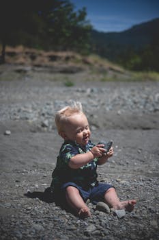 可爱的宝宝在阳光明媚的户外玩石头