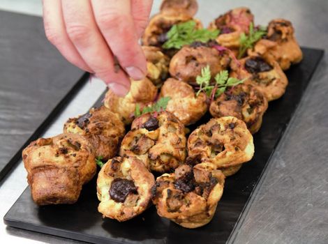 Freshly baked savory muffins being garnished by hand, offering a delightful culinary experience.